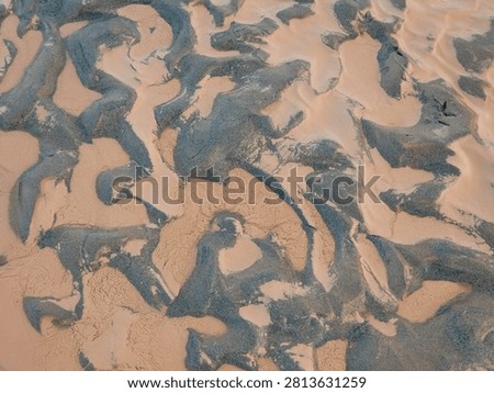 Abstract sand patterns on a beach. Natural textured background of wet dark sand and silt.