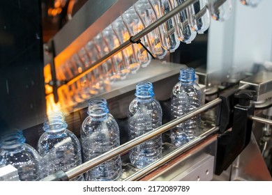 The abstract scene of plastic processing of PET bottles in the drinking water factory. The hi-technology of plastic bottle manufacturing process. - Shutterstock ID 2172089789