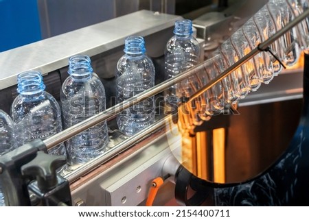 The abstract scene of plastic processing of PET bottles in the drinking water factory. The hi-technology of plastic bottle manufacturing process.