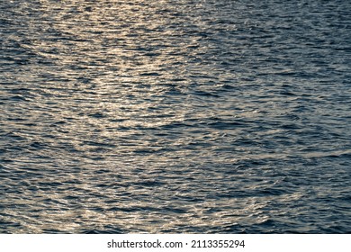 Abstract sea water waves background or texture during sunset, view on ripple surface