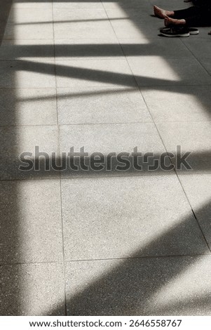 Abstract shadow pattern of railing on pedestrian bridge floor during sunny day.