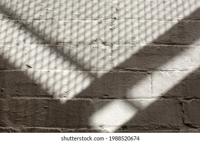 Abstract Shadow Pattwerns Being Cast By The Strairs Of An External Fire Escape Outside A Building