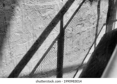 Abstract Shadow Pattwerns Being Cast By The Strairs Of An External Fire Escape Outside A Building