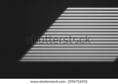 Abstract shadow of window blinds creating parallel lines on a dark wall, evoking a minimalist and moody aesthetic