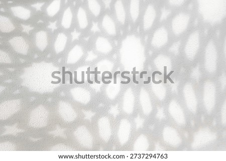 Abstract shadows of Islamic geometric patterns softly cast on a light textured wall, creating a serene, minimalist background with a calm spiritual mood for Ramadan and Eid Mubarak