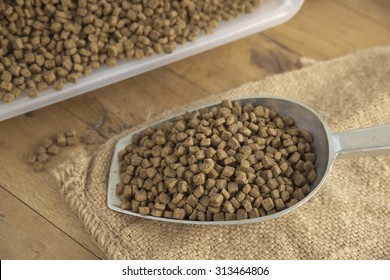 Abstract Shallow DOF Closeup Of Spoonful Of Premium Grade Dog Food Over Agriculture Sack On Top Of Wooden Board With Plastic Container In Background