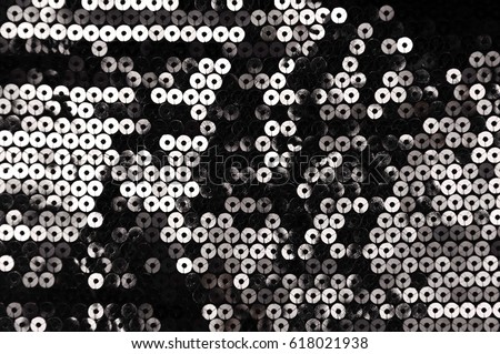 Abstract shiny  background with silver sparkles, texture of beautiful fashion fabric with black sequins

