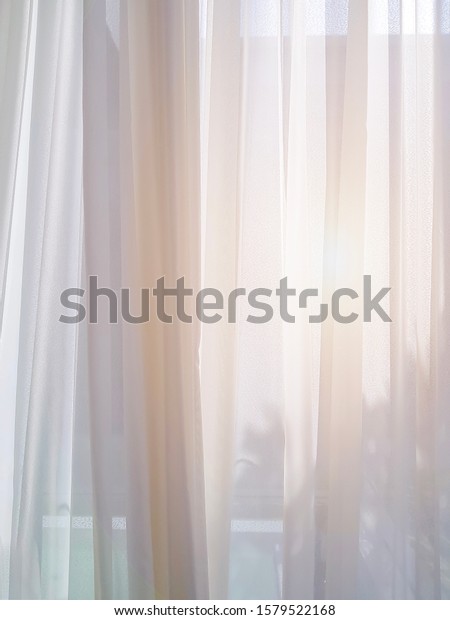 Abstract\
silhouette scene with white sheer curtain inside window in living\
room, white sheer curtain bright up with sun flare outside to\
inside, soft and light pleats fabric\
pattern.