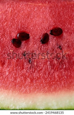 abstract of sliced watermelon surface, bright red tone fresh juicy watermelon with black seeds background in full frame, wallpaper or backdrop in macro view
