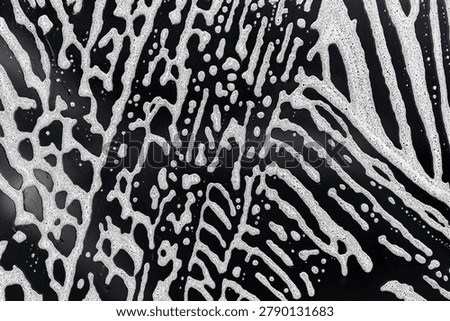 Abstract soap foam pattern on dark surface. White bubbles texture closeup. Cleaning background with organic shapes. Washing and hygiene concept. High contrast abstract design.