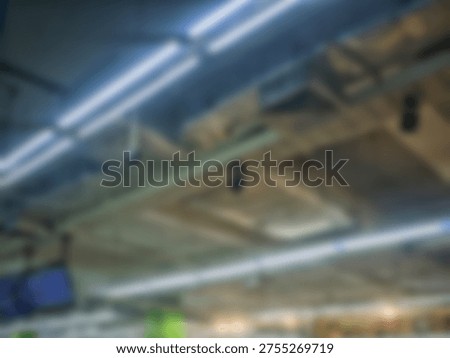 Abstract soft focus view of bright overhead light tubes installed on a commercial building ceiling structure.