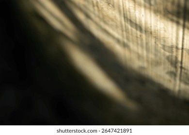 An abstract, soft-focus image of a diagonal beam of warm sunlight falling across a wooden surface. A dreamy, peaceful, and mysterious background with strong light and shadow.

