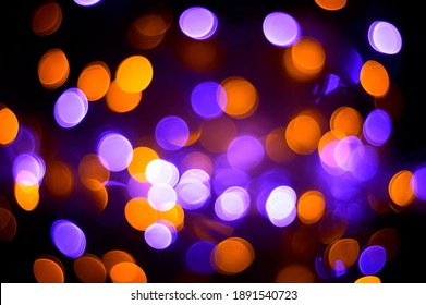 Abstract Sparkling Defocus Background With Yellow And Purple Lights On Black. Beautiful Colored Bokeh Background