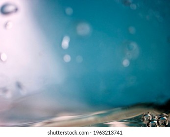 Abstract sparse blue bubbles background. Bright light shinning on water waves in empty blue space with water bubbles in bottom left corner.