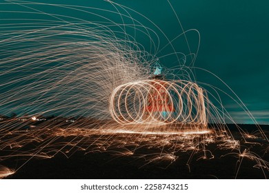 Abstract steel wool photography. The image is taken by lighting steel wool on fire, spinning the fire and walking while taking a long exposure photo will creat a spiral of light. - Shutterstock ID 2258743215