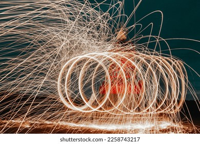 Abstract steel wool photography. The image is taken by lighting steel wool on fire, spinning the fire and walking while taking a long exposure photo will creat a spiral of light. - Shutterstock ID 2258743217