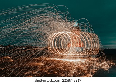 Abstract steel wool photography. The image is taken by lighting steel wool on fire, spinning the fire and walking while taking a long exposure photo will creat a spiral of light. - Shutterstock ID 2258743219