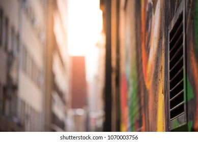 Abstract style photograph looking down a graffiti lined alley way towards the sun. Johannesburg inner city