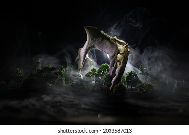 Abstract surreal concept. Giant animal bone in dark forest under moonlight. Night with fog and light on background. Selective focus