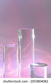 Abstract Surreal Scene - Empty Stage With Three Clear Glass Cylinder Podiums On Pastel Pink Holographic Background. Pedestal For Cosmetic Product Packaging Mockups Display Presentation