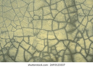 An abstract texture background of a cracked surface. The fine network of crazing on the faded, yellowish-green paint creates a pattern resembling dry earth or old ceramic glaze