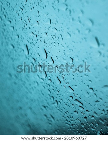 Abstract texture background featuring numerous water droplets and rivulets running down a pane of glass