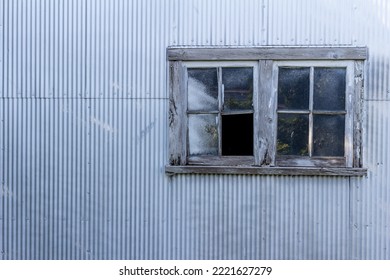 Abstract Texture Background Of A Rustic Old Wood Framed Glass Window On A Corrugated Metal Shed Wall, With A Grungy Shabby Chic Appearance