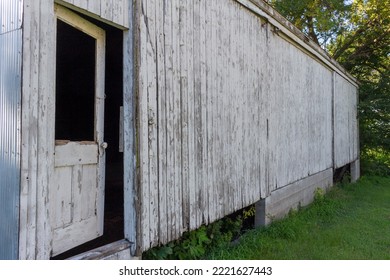 Abstract Texture Background Of A Rustic Old Wooden Door On A Deteriorating Wood And Corrugated Metal Shed Wall, With A Grungy Appearance