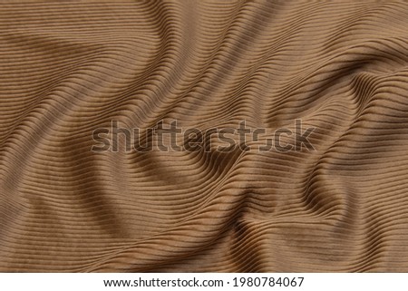 Abstract texture of natural beige or brown color fabric as concept background. Fabric texture of natural cotton or linen, silk or satin, wool or jersey textile material. Luxurious dark background.
