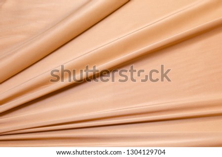 Abstract texture of natural orange, peach or apricot color fabric as concept background. Fabric texture of natural cotton or linen, silk or satin, wool or jersey textile material. Luxurious background