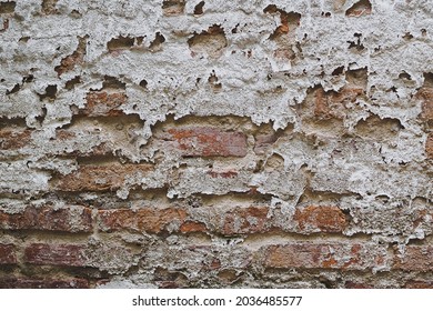Abstract texture of old white wall with peel off and damanged by weather showed orange brick inside