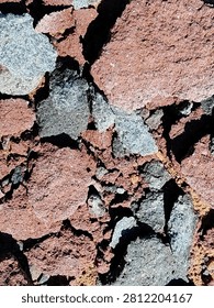 Abstract texture of red volcanic rocks and grey stone fragments.