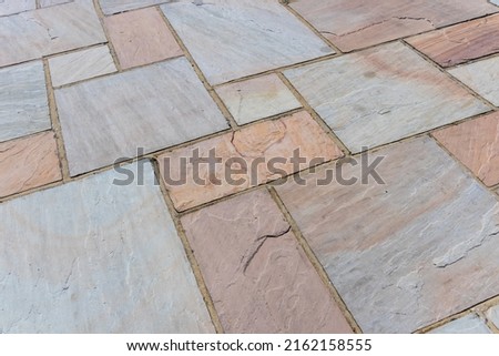 Abstract texture of red, yellow and grey toned Indian sandstone paving