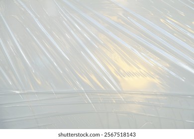 Abstract texture of translucent plastic wrap with light reflections creating interesting patterns and lines.