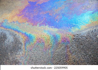 The Abstract Textured Pattern Of An Oil Or Petrol Slick On Wet Asphalt Of The Road