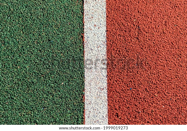 Abstract textured sport field background. Top view of\
green and red rubber turf surface with white line between them.\
Copy space. 
