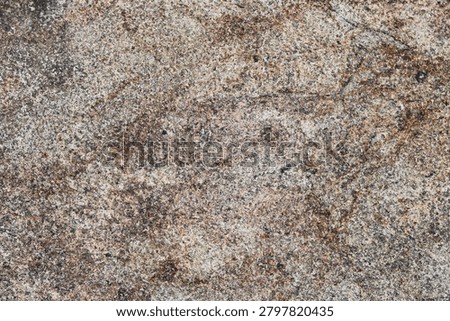An abstract textured stone background featuring a blend of grey, warm tan, light beige, and thin veins of rusty brown, with natural grain patterns, speckles, and subtle surface cracks.