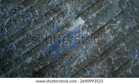 Abstract textured surface features navy and gray colors with blue striations, creating a weathered, distressed look with soft lighting, ideal for artistic backgrounds or design elements.