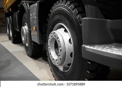 Abstract Tipper Truck Wheels And Tires With Blured Background. Truck Wheel Rim. Truck Chassis Exhibit On Car Exhibition. Commercial Transport With Special Truck Wheels Mud Tires