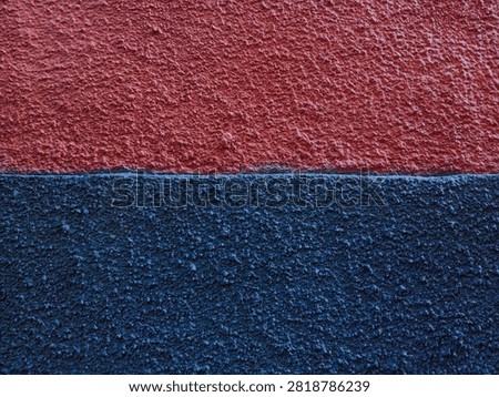 Abstract two tone red and dark blue stucco wall texture background with horizontal split line and rough plaster surface.