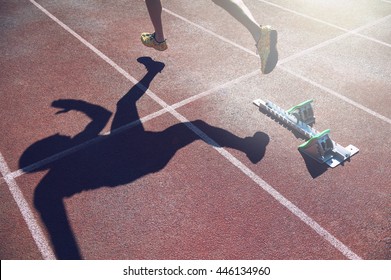 Abstract View Of Athlete In Gold Shoes Sprinting From The Starting Line Blocks Of A Race On A Red Running Track 