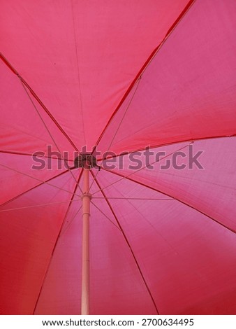 Abstract view from below of a vibrant red pink umbrella structure texture pattern geometry protection from sun rain