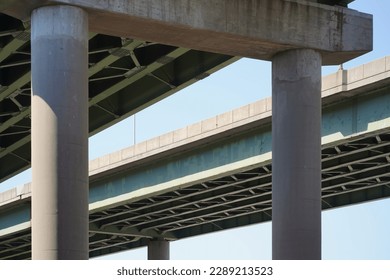 Abstract view of elevated interstate highway from below. Concrete pillars with green steel beam infrastructure
