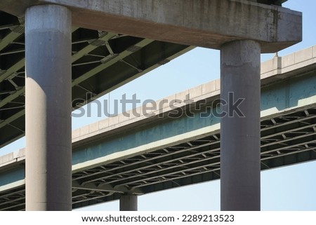 Abstract view of elevated interstate highway from below. Concrete pillars with green steel beam infrastructure