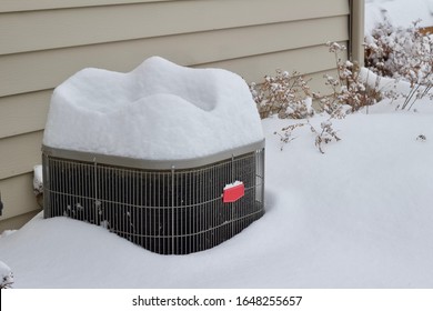 Abstract view of an exterior home air conditioning unit covered with deep snow following a blizzard