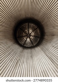Abstract view looking up into a ribbed cylindrical structure with a circular metal center, creating a strong radial pattern and industrial geometric texture.