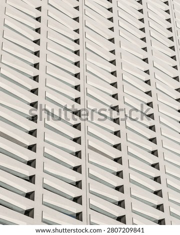 Abstract view of a modern building facade with repeating geometric patterns and angled windows.