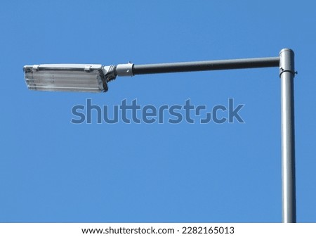 abstract view of modern street lamp with square head under blue sky in perspective view on pewter color tubular light pole. blue sky background. street lighting technology concept.