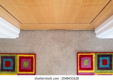 Abstract View Of A Multicoloured Pair Of Carpet Mats Seen By The Entrance Of A Closed Bathroom Door.