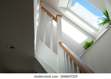 Abstract view of a newly installed loft conversion seen from the ground floor, looking at the staircase. A skylight window is seen on a sunny day. - Shutterstock ID 2048437229